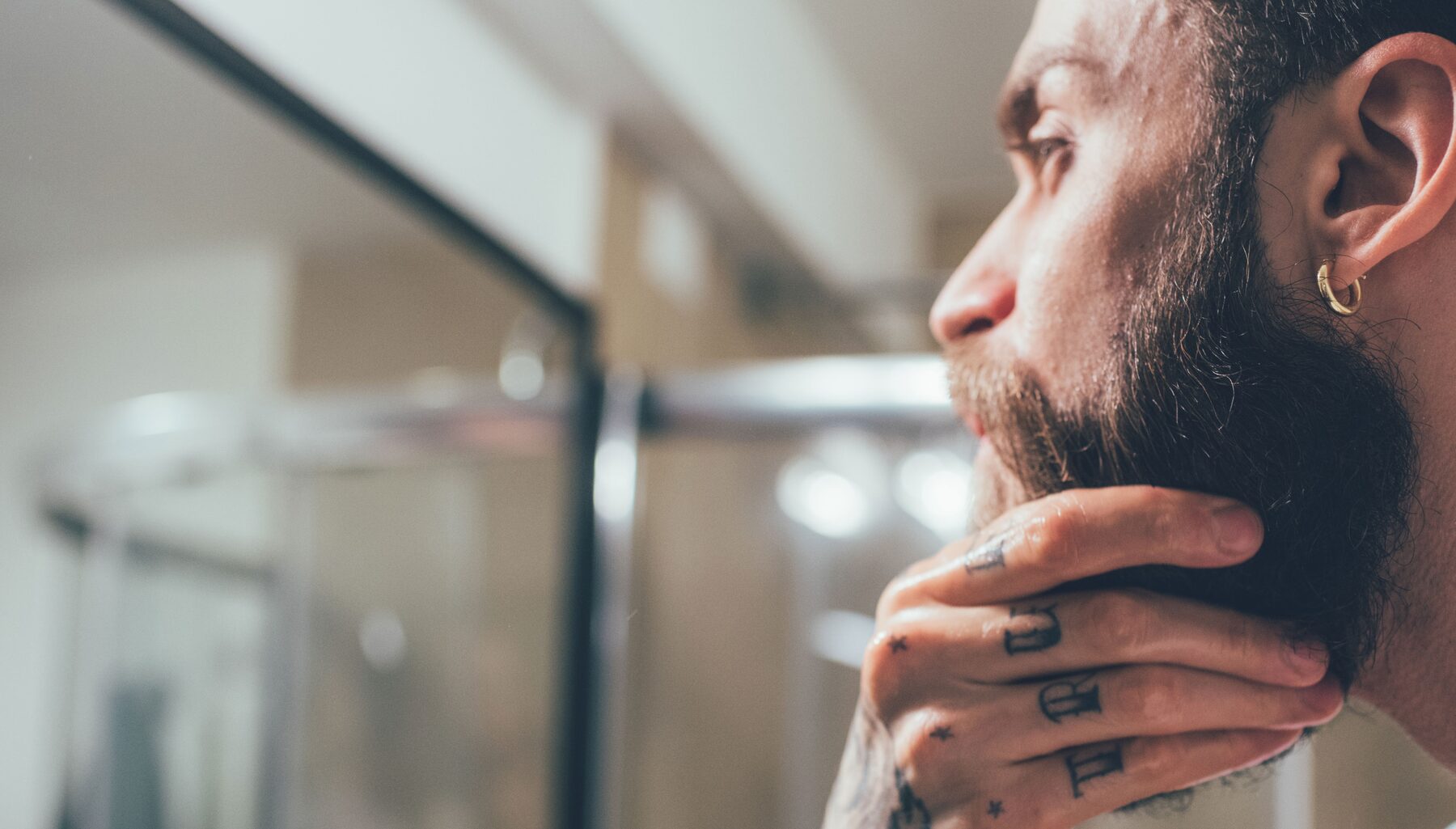 Man conditioning his beard in the mirror